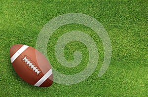 American football ball on grass field background.