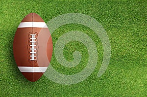 American football ball on grass field background.