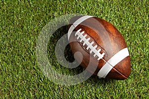 American football ball on green grass field background.