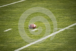 American Football field. Grass field with a football resting on the yard marker.