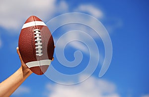 American Football in Hand over Sky