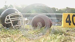 American football helmet and ball lying on pitch, summer camp sport activities