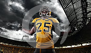 American football player, athlete in helmet with ball on stadium. Sport wallpaper with copyspace.