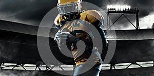 American football player, athlete in helmet with ball on stadium. Sport wallpaper with copyspace.