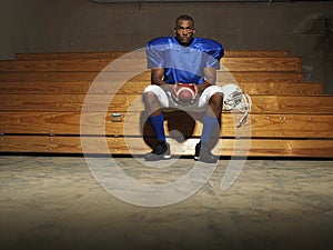 American Football Player With Ball On Bench