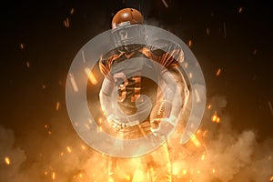 American football player on dark background in smoke and sparks in black and orange outfit