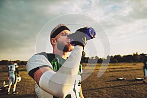 American football player drinking water during a team practice
