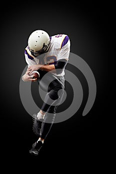 American football player in a jump with a ball on a black background