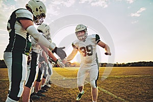 American football player low fiving his teammates after practice