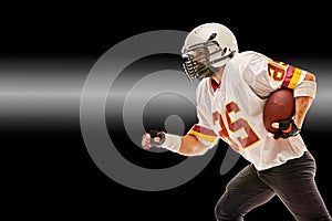 American football player in motion with the ball on a black background with a light line, copy space. The concept of the