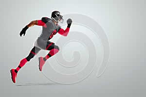 American Football player in red and black uniform in running pose on white background. American Football, advertising poster,