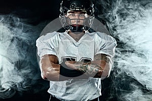American football player, sportsman in helmet on black background with smoke. Sport and motivation wallpaper.