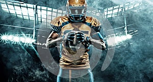 American football player on stadium with ball in hands and helmet on head. Sports background and wallpaper. Black skin