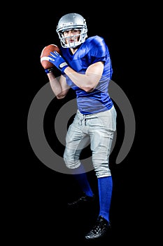 American football player throwing ball over black background