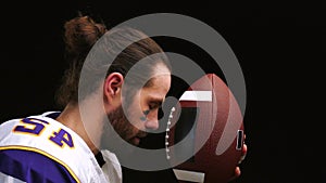 American Football Player who gently hold and kiss his ball and mentally reads a prayer before the match