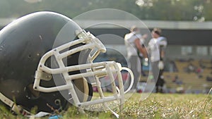 American football players having break on field, drinking water, communicating