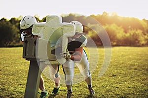 American football players practicing with tackling sled on a fie