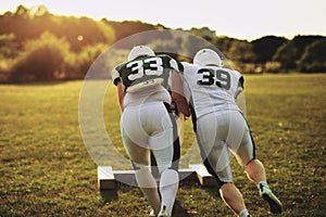 American football players pushing a tackling slide on a field