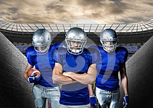 American football players standing against stadium in background