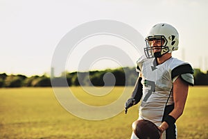 American football quarterback standing on a field holding a ball photo