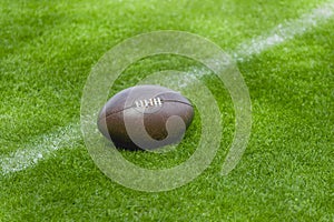 American football, rugby ball on green grass field background