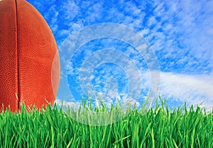 American football (rugby ball) on green grass over blue sky