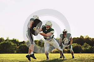 American football teammates practicing defensive tackles on a sp