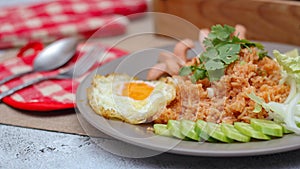 American fried rice served with sausages, cucumbers, shredded vegetables in a gray plate on a white table with seasoning