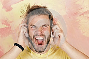 American handsome bearded guy with headphones. Cheerful teenage dj listening songs via earphones. Blue eyed stylish