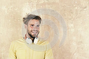 American handsome bearded guy with headphones. Cheerful teenage dj listening songs via earphones. Blue eyed stylish