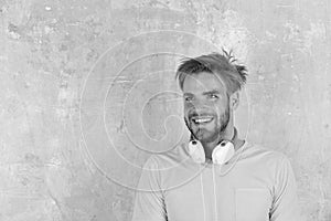 American handsome bearded guy with headphones. Cheerful teenage dj listening songs via earphones. Blue eyed stylish