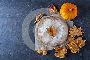 American homemade pumpkin or apple pie with walnut and autumn dry leaves on rustic table. Thanksgiving dish. Autumn harvest