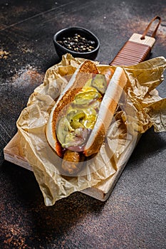 American hot dog with pork sausage on a wooden cutting Board in Kraft paper, fast food restaurant menu concept. Junk