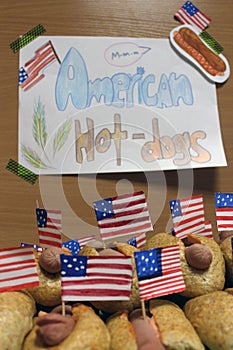 American hot dogs with small American flags close plan, bun and sausage and an inscription american hot dogs on paper