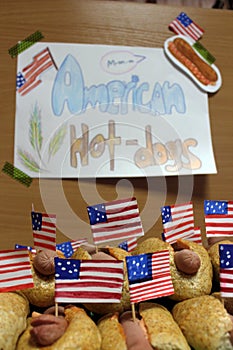 American hot dogs with small American flags close plan, bun and sausage and an inscription american hot dogs on paper