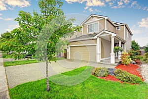 American house exterior with garage, driveway and well kept lawn.