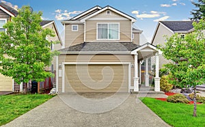 American house exterior with garage, driveway and well kept lawn.