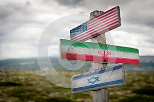 American, iranian and israelian national flags painted on wooden rustic signpost outdoors