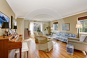 American living room interior with piano, blue sofa and hardwood floor.