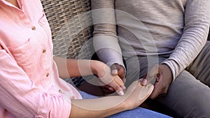 American loving couple holding hands sitting on bench, trusting relationships