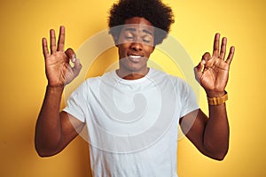 American man with afro hair wearing white t-shirt standing over isolated yellow background relax and smiling with eyes closed