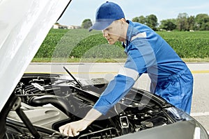 American mechanic checking car on roadside