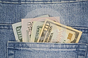 American money dollars in various denominations peep out of a jeans pocket.