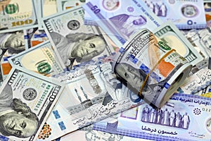 American money roll with a band on a pile of American dollar bills American cash money banknotes with Saudi Arabia riyals money