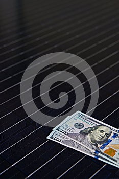 American money on solar panel surface. Renewable energy cost