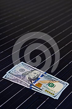 American money on solar panel surface. Renewable energy cost