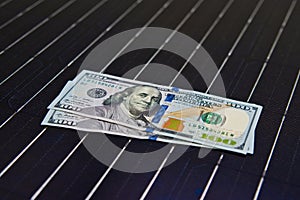 American money on solar panel surface. Renewable energy cost