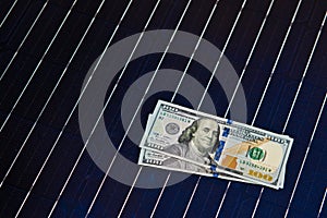 American money on solar panel surface. Renewable energy cost