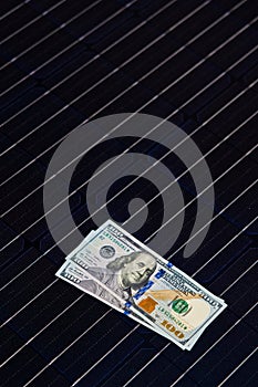 American money on solar panel surface. Renewable energy cost