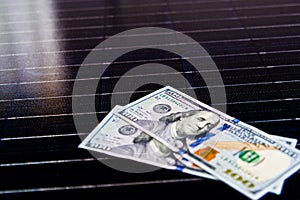 American money on solar panel surface. Renewable energy cost
